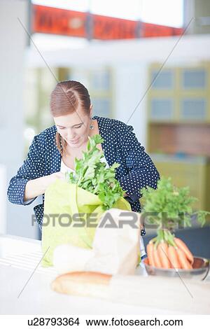 Young woman looking in grocery bags View Large Photo Image Picture - Young woman looking in grocery bags. Fotosearch
