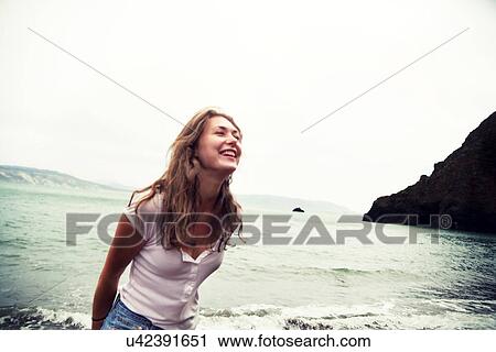 Stock Image - Young woman on beach, smiling. Fotosearch