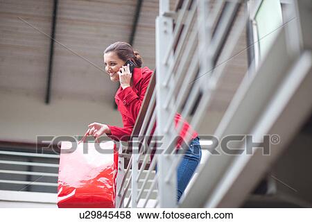 Stock Photo - Young woman on cellphone in shopping mall. Fotosearch