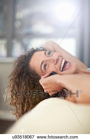 Stock Photo - Young woman on cellphone, laughing. Fotosearch