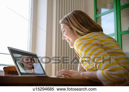 Stock Photography - Young woman on video call with friend. Fotosearch