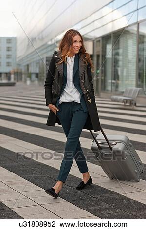 Young woman outside airport with trolley case View Large Photo Image Stock Image - Young woman outside airport with trolley case. Fotosearch