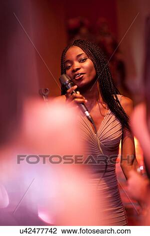 Young woman singing with microphone View Large Photo Image Stock Image - Young woman singing with microphone. Fotosearch