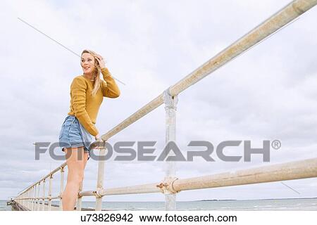 Young woman standing on pier View Large Photo Image Stock Image - Young woman standing on pier. Fotosearch
