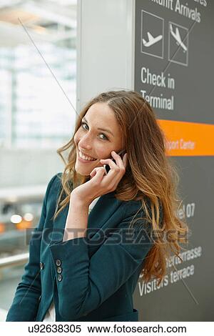 Stock Photography - Young woman using mobile at airport. Fotosearch