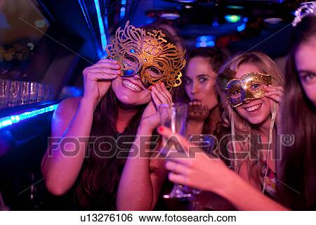 Stock Photograph - Young woman wearing mask in limousine. Fotosearch