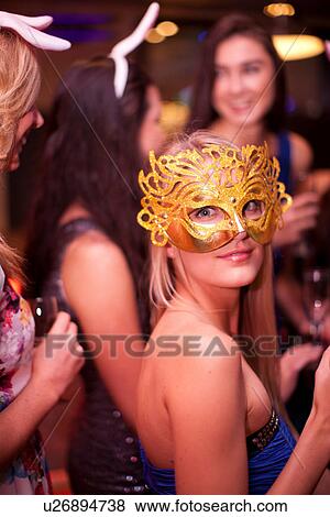 Stock Photo - Young woman wearing masquerade mask at hen party. Fotosearch