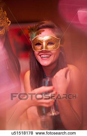 Stock Photo - Young woman wearing masquerade mask at hen party. Fotosearch