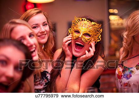 Stock Photo - Young woman wearing masquerade mask at hen party. Fotosearch