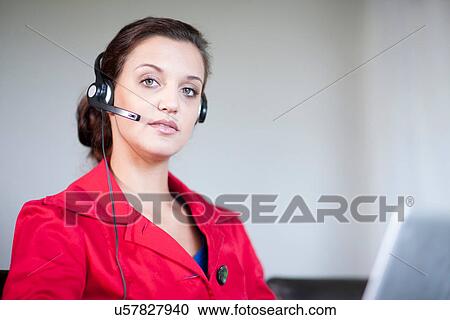 Stock Image - Young woman wearing telephone headset. Fotosearch