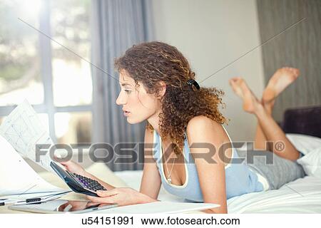 Stock Image - Young woman with calculator and paperwork. Fotosearch