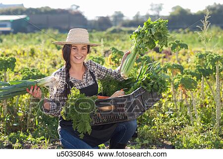 Stock Photography - Young woman with vegetables grown at farm. Fotosearch