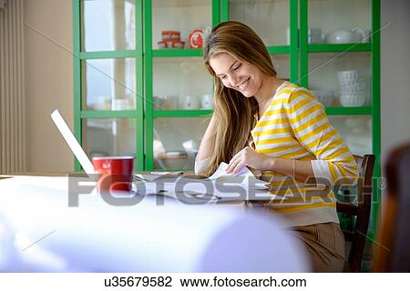 Stock Image - Young woman working from home. Fotosearch