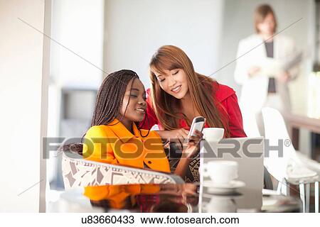 Young women looking at cell phone View Large Photo Image Stock Image - Young women looking at cell phone. Fotosearch