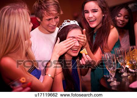Stock Image - Young women playing drinking game at hen party. Fotosearch