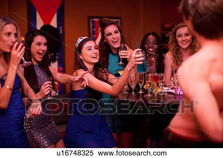 Stock Photography - Young women watching male stripper at hen party. Fotosearch