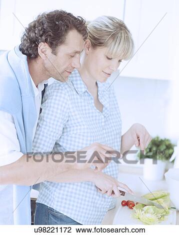 Stock Image - A couple making a healthy salad in the kitchen. Fotosearch