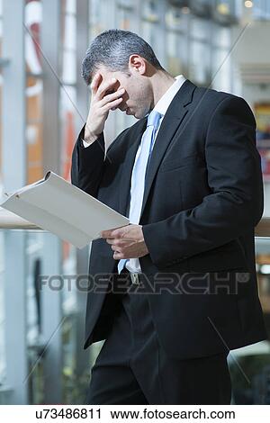 Business man reads document and covers face View Large Photo Image Stock Image - Business man reads document and covers face. Fotosearch