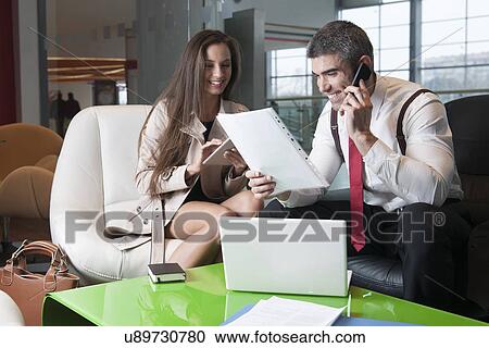 Stock Image - Businessman and businesswoman at meeting with laptop and tablet. Fotosearch
