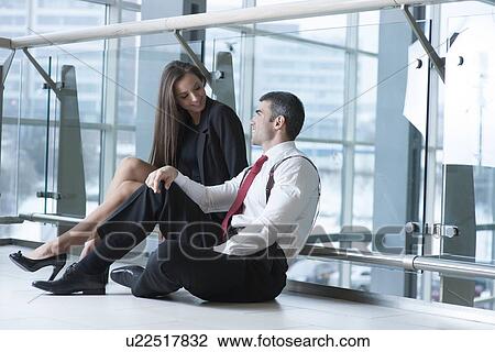 Businessman and businesswoman sitting on the ground talking View Large Photo Image Stock Image - Businessman and businesswoman sitting on the ground talking. Fotosearch