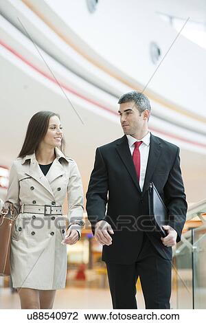 Stock Image - Businessman and businesswoman walking together. Fotosearch