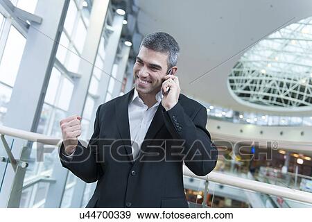 Stock Photo - Businessman celebrates talking on mobile phone. Fotosearch