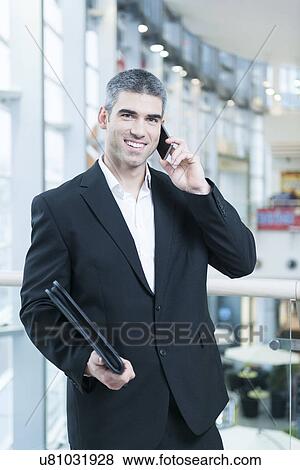 Businessman on mobile phone looking at camera View Large Photo Image Stock Photo - Businessman on mobile phone looking at camera. Fotosearch