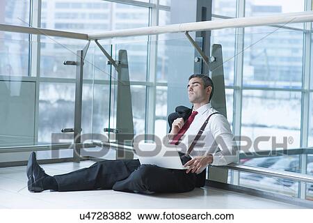 Businessman sitting on ground asleep with laptop View Large Photo Image Stock Image - Businessman sitting on ground asleep with laptop. Fotosearch