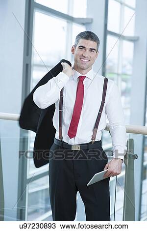 Businessman smiling and looking at camera with jacket over shoulder View Large Photo Image Stock Image - Businessman smiling and looking at camera with jacket over shoulder. Fotosearch