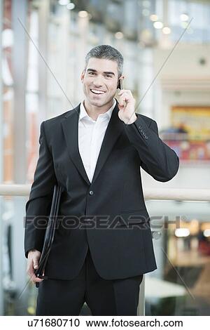 Stock Image - Businessman talking on mobile phone. Fotosearch