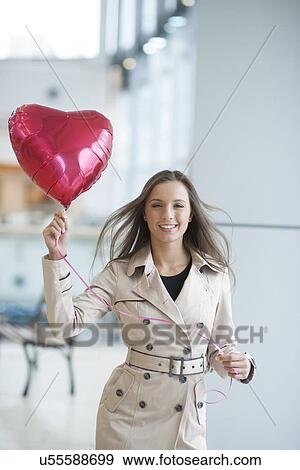Businesswoman holding heart shaped balloon and smiling View Large Photo Image Stock Photo - Businesswoman holding heart shaped balloon and smiling. Fotosearch