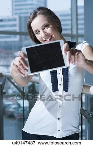 Stock Photo - Businesswoman holds up tablet device to camera. Fotosearch