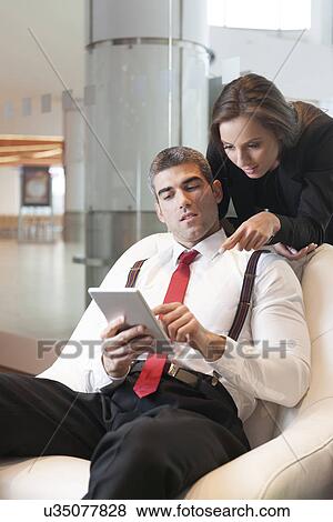 Businesswoman looking over male colleagues shoulder pointing at digital tablet View Large Photo Image Stock Photo - Businesswoman looking over male colleagues shoulder pointing at digital tablet. Fotosearch