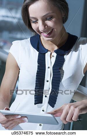Businesswoman smiling and reading from tablet View Large Photo Image Stock Photography - Businesswoman smiling and reading from tablet. Fotosearch