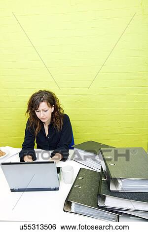 Caucasian young woman working on her laptop computer at her desk View Large Photo Image Stock Photograph - Caucasian young woman working on her laptop computer at her desk. Fotosearch