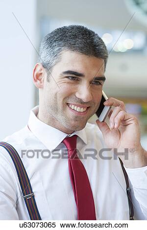 Stock Photography - Close-up of businessman smiling on mobile phone. Fotosearch