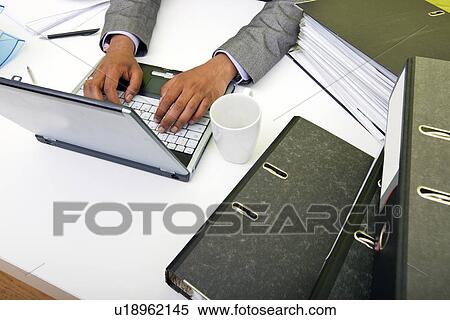 Close up of Indian mans hands typing on laptop with folders and mug View Large Photo Image Stock Photography - Close up of Indian mans hands typing on laptop with folders and mug. Fotosearch