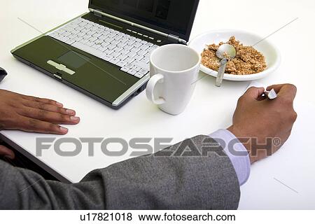 Stock Photo - Close up of Indian mans hands writing on paper next to cereal. Fotosearch