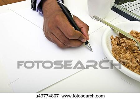 Close up of Indian mans hands writing on paper next to cereal View Large Photo Image Stock Photo - Close up of Indian mans hands writing on paper next to cereal. Fotosearch