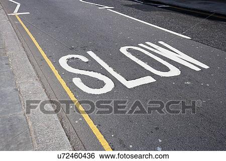 Stock Photograph - Close-Up of road marking saying Slow in London, UK. Fotosearch