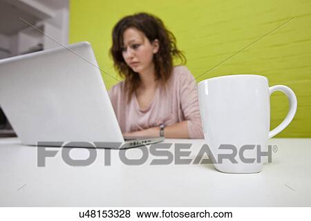 Close up of womans hands typing on laptop with mug in foreground View Large Photo Image Stock Photo - Close up of womans hands typing on laptop with mug in foreground. Fotosearch