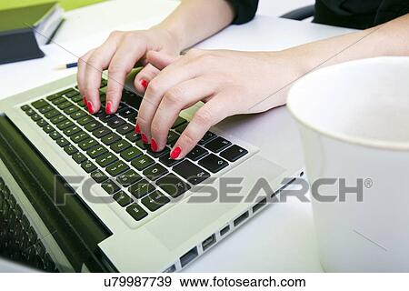 Close up of womans hands typing on laptop with mug in foreground View Large Photo Image Stock Photo - Close up of womans hands typing on laptop with mug in foreground. Fotosearch