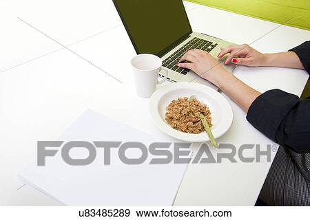 Stock Photo - Close up of womans hands typing on laptop with mug in foreground. Fotosearch