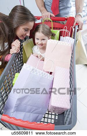 Close-up of young daughter in trolley being pushed by father and mother View Large Photo Image Stock Image - Close-up of young daughter in trolley being pushed by father and mother. Fotosearch