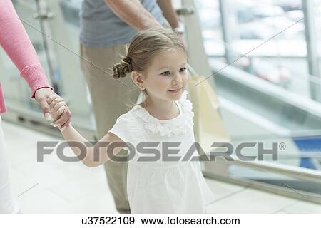 Stock Photo - Close-up of young girl holding parents hands . Fotosearch