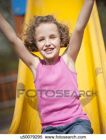Stock Photography - Close-up view of young girl on slide in playground. Fotosearch