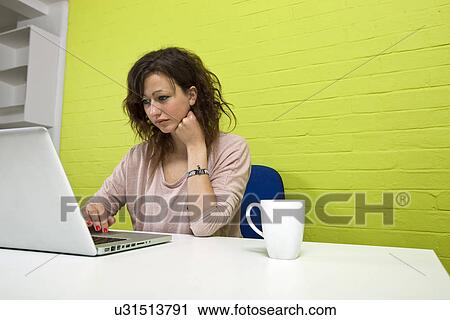 Stock Image - Close-up view of Young woman working at her desk. Fotosearch