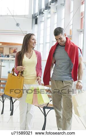 Couple with shopping bags in mall View Large Photo Image Stock Image - Couple with shopping bags in mall. Fotosearch