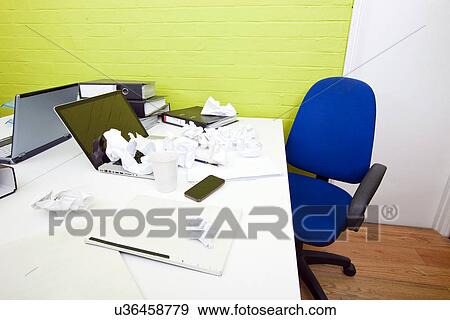 Stock Photo - Crumpled paper over laptop on desk with empty chair and folders. Fotosearch