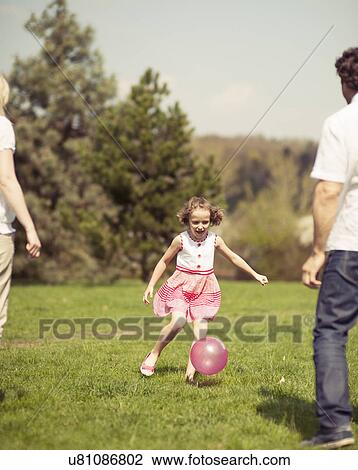 Daughter kicking ball to father and mother in park View Large Photo Image Stock Image - Daughter kicking ball to father and mother in park. Fotosearch